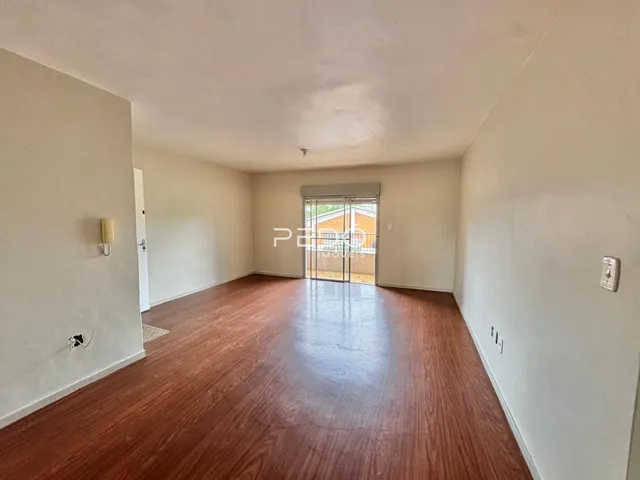 Interior de uma sala com piso de madeira e paredes brancas.