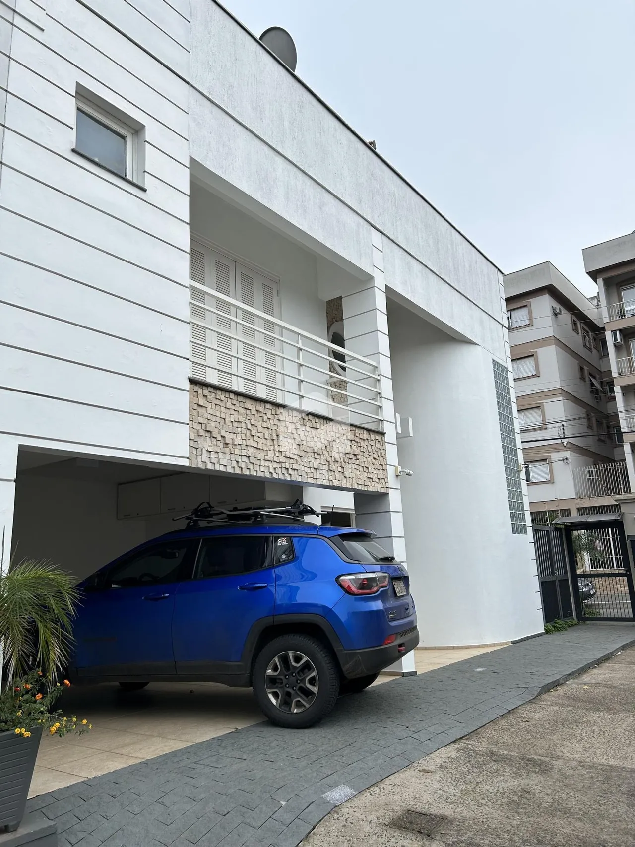 Fachada de um imóvel branco com varanda e revestimento de pedra.