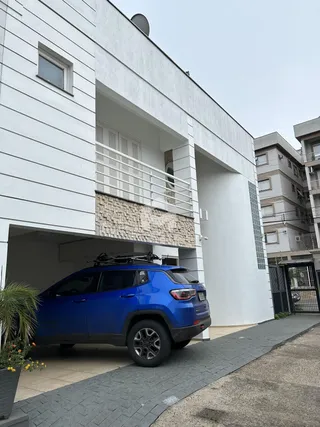 Fachada de um imóvel branco com varanda e revestimento de pedra.