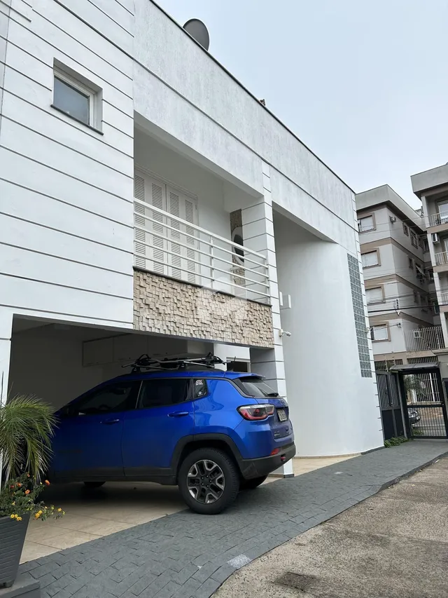 Fachada de um imóvel branco com varanda e revestimento de pedra.