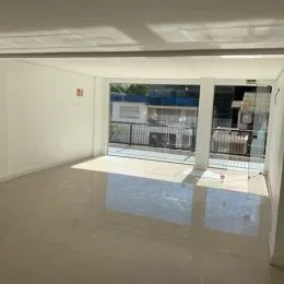 Vista interna de um espaço amplo com piso claro e paredes brancas.