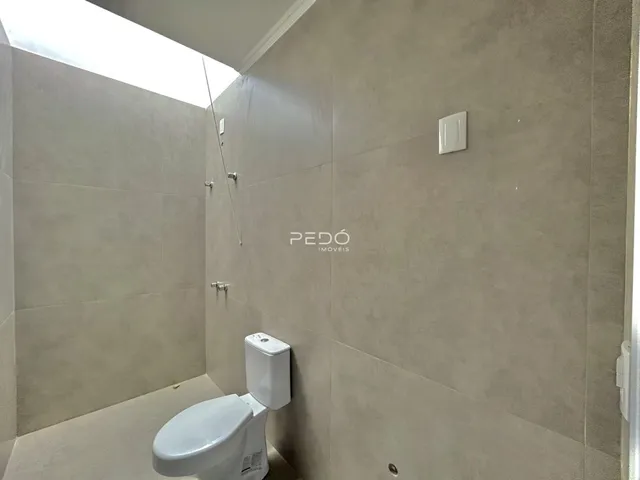 Foto de um banheiro com revestimento claro e louças brancas.