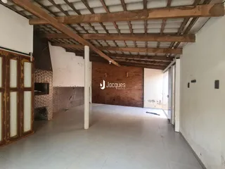 Interior de um espaço com vigas de madeira expostas e piso de cerâmica.
