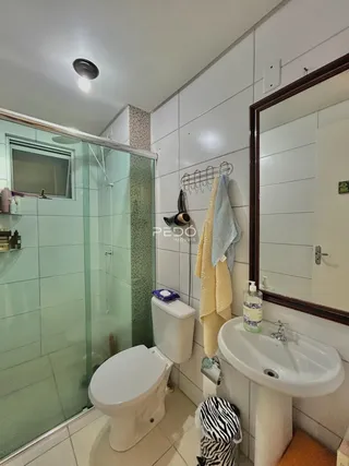 Foto de um banheiro com box de vidro e revestimento de azulejos claros.