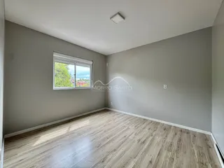 Foto de uma sala com piso de madeira clara e janela.