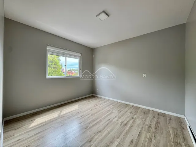 Foto de uma sala com piso de madeira clara e janela.