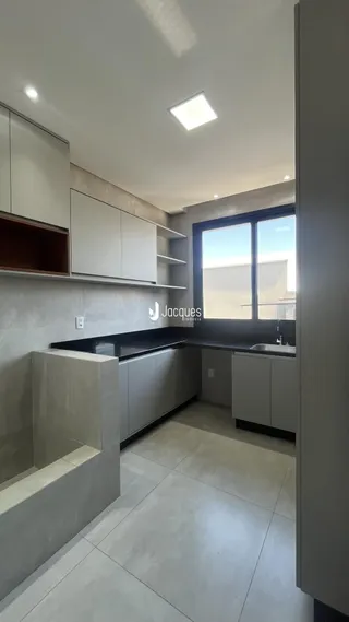 Vista da cozinha moderna com armários brancos e bancadas escuras.