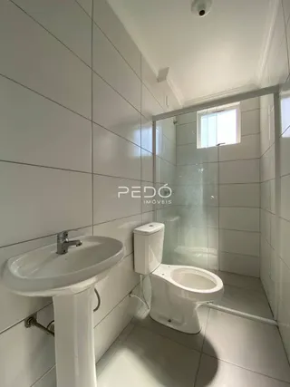 Foto de um banheiro com box de vidro e louças brancas.