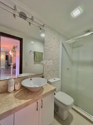Banheiro moderno com bancada dupla e box de vidro.