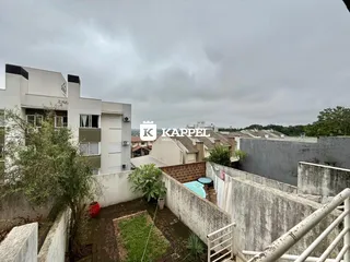 Vista externa de um pátio com muro de concreto e vegetação.