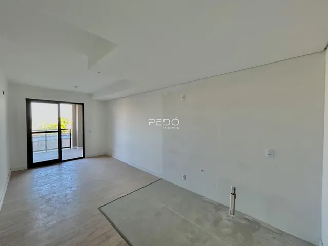 Ambiente interno de uma sala ampla com piso de madeira e porta de vidro.