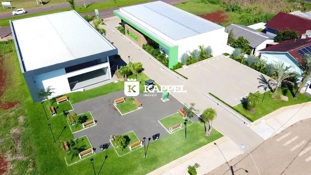 Vista aérea de uma propriedade com um edifício grande e área externa pavimentada.