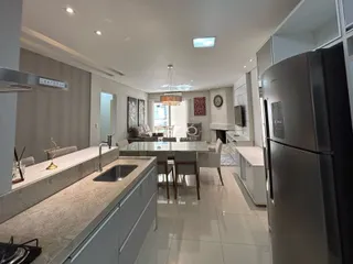 Vista de uma cozinha moderna com ilha e área de jantar em um apartamento.