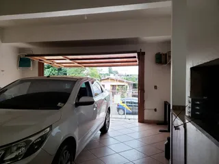 Vista de um interior com uma porta aberta para uma área externa onde um carro está estacionado.
