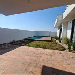 Foto da área externa mostrando uma piscina azul e um pátio.