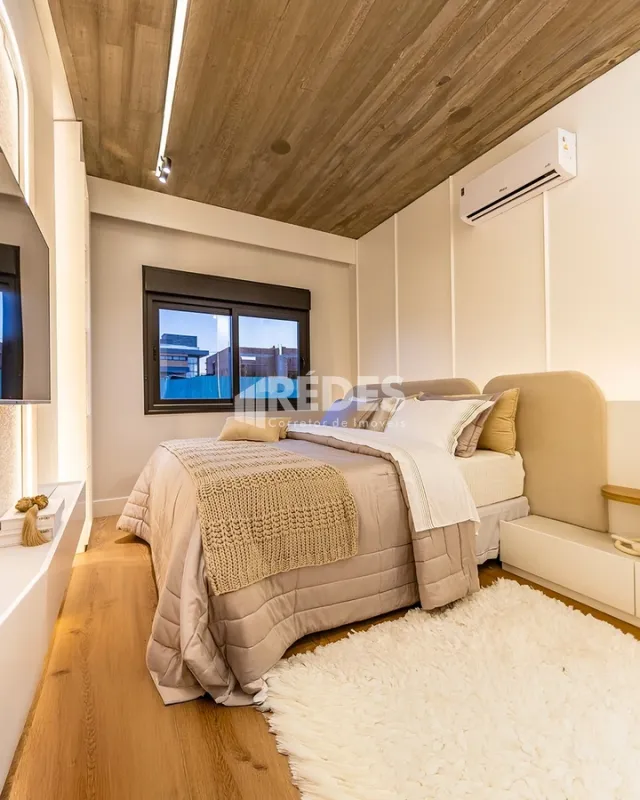 Quarto com piso de madeira e cama bem arrumada.