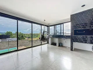 Sala de estar ampla com grandes janelas que oferecem uma vista externa.