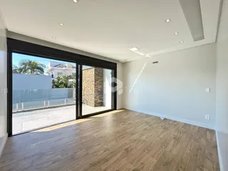 Sala de estar com piso de madeira clara e porta de vidro que dá para o exterior.