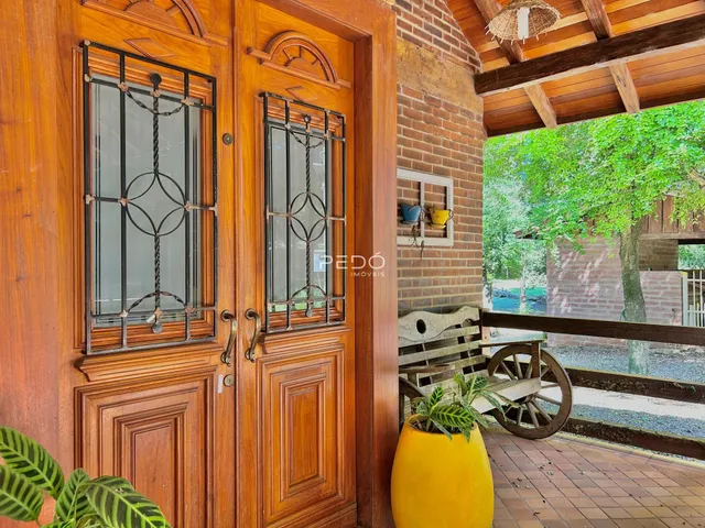 Porta de madeira com ferro forjado em uma área externa com parede de tijolos.