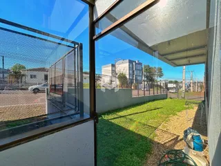 Vista externa de um quintal gramado e área cercada de uma residência.