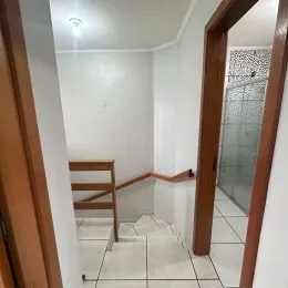 Corredor interno com paredes brancas e piso de cerâmica.