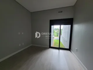 Vista interna de uma sala com piso de madeira clara e porta de vidro.