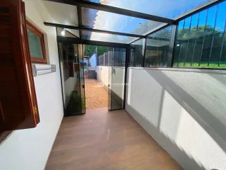 Ambiente interno com piso de madeira e grandes painéis de vidro.