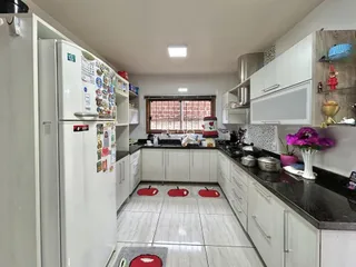 A foto mostra o interior de uma cozinha com armários brancos e piso claro.