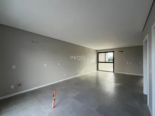 Um espaço interno amplo com paredes cinzas e piso claro.