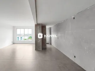 Foto de um espaço interno amplo e vazio com paredes brancas e piso claro.