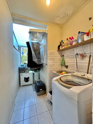 Vista de uma área de serviço com máquina de lavar roupa e janela.