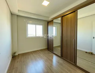 Interior de uma sala com piso de madeira clara e parede neutra.