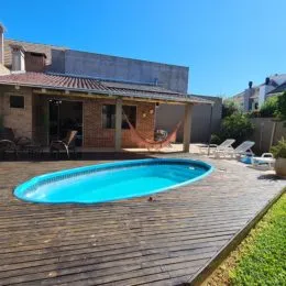 Foto da piscina externa com deck de madeira em uma propriedade.