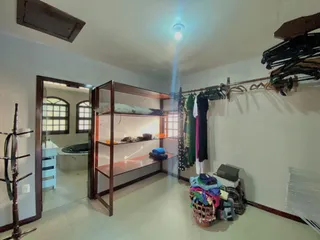 Um quarto com estantes de madeira e roupas penduradas.