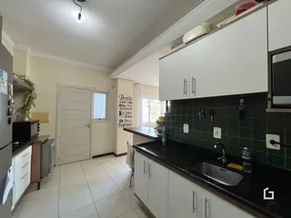 Foto de uma cozinha com armários brancos e bancada escura.
