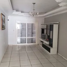 Foto interna de uma sala com piso de cerâmica e portas de vidro.