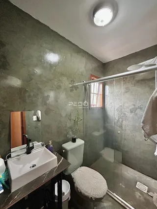 Foto de um banheiro com box de vidro e vaso sanitário em um imóvel.