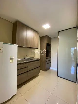 Cozinha com armários de madeira e piso claro.