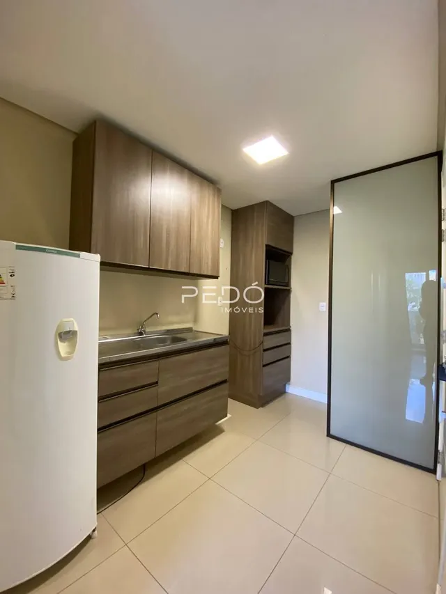 Cozinha com armários de madeira e piso claro.