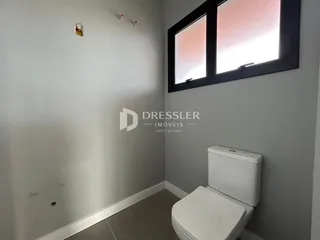 Parede interna de um banheiro com janela e vaso sanitário.