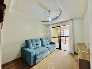 Sala de estar com sofá azul e piso de madeira em um imóvel no Brasil.
