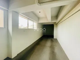 Vista interna de um corredor com paredes brancas e piso de concreto.