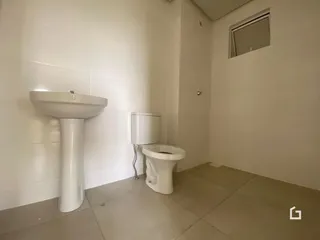 Foto de um banheiro com pia e vaso sanitário em paredes brancas.