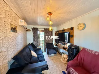Sala de estar com sofá e televisão em ambiente interno.