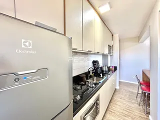Cozinha moderna com armários brancos e bancada preta em imóvel no Brasil.