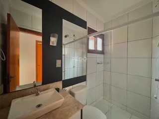 Banheiro com box de vidro e revestimento cerâmico nas paredes.