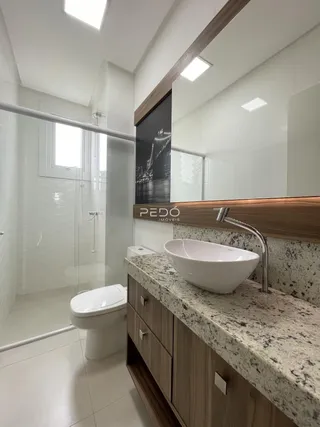 Banheiro moderno com box de vidro e bancada de granito.