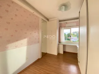Interior de uma sala com piso de madeira e papel de parede rosa.