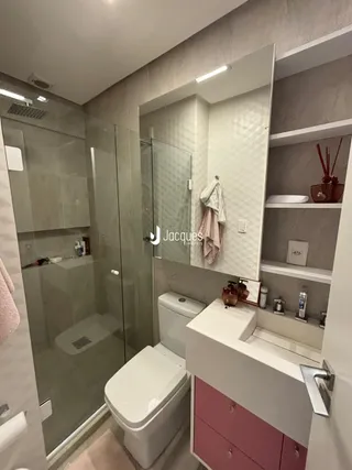 Banheiro moderno com box de vidro e louças brancas.
