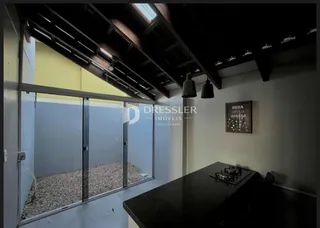 Vista interna de um cômodo com estrutura de teto exposta e porta de vidro.